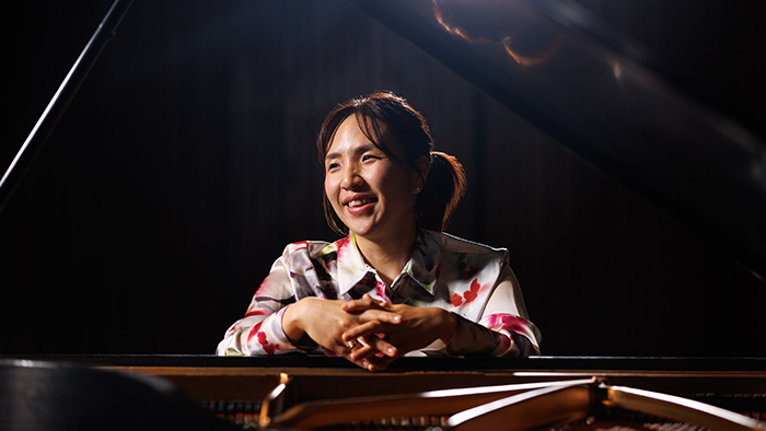 Smiling woman leaning over a piano.
