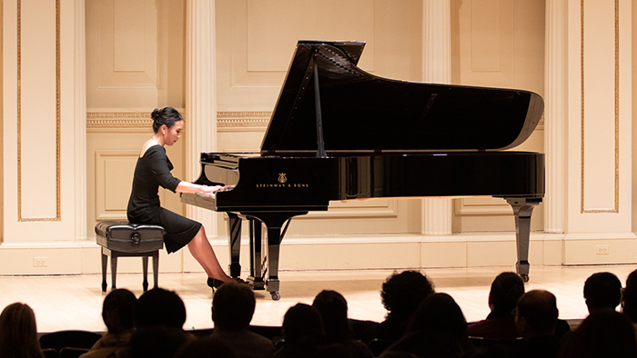 Woman playing piano in front of an audience.