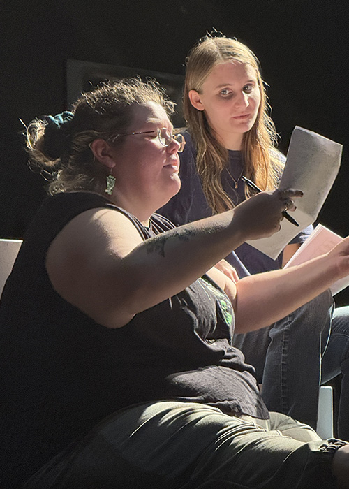 Two girls looking at notes during a class.