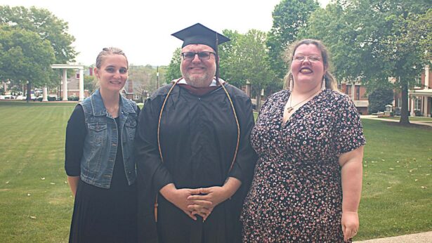 Three people smiling for a photo after a graduation ceremony.