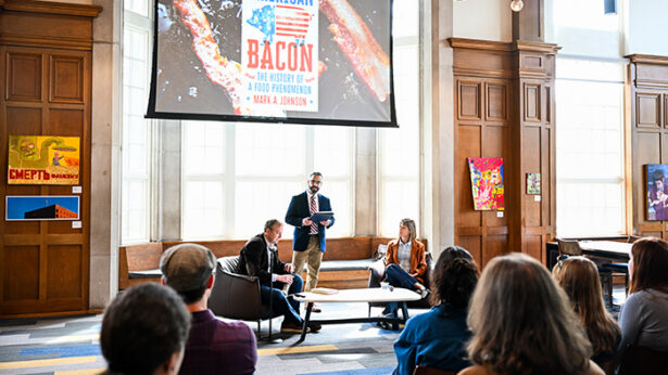 Two people and a moderator talking in front of an audience.