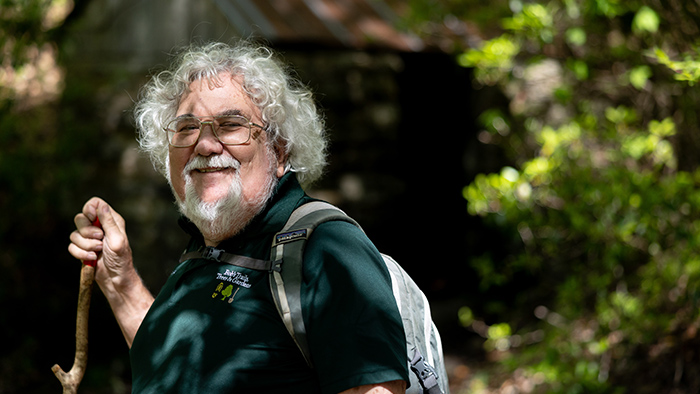 Man holding a walking stick while on a mountain trail.