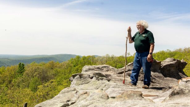 Man enjoying the view from a mountain top trail.