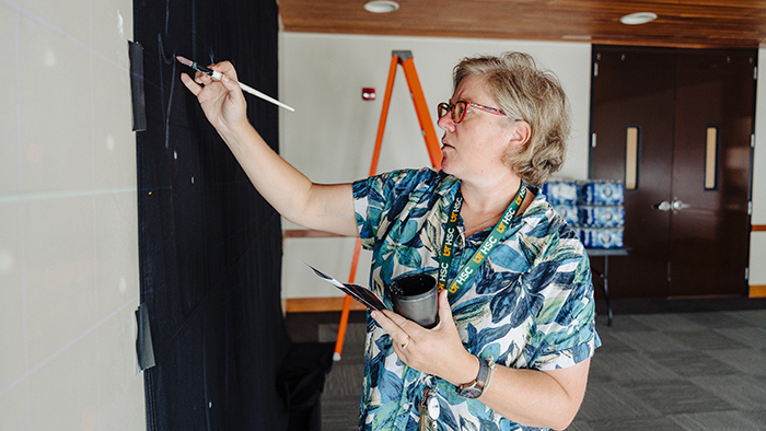 A woman painting on a large canvas.