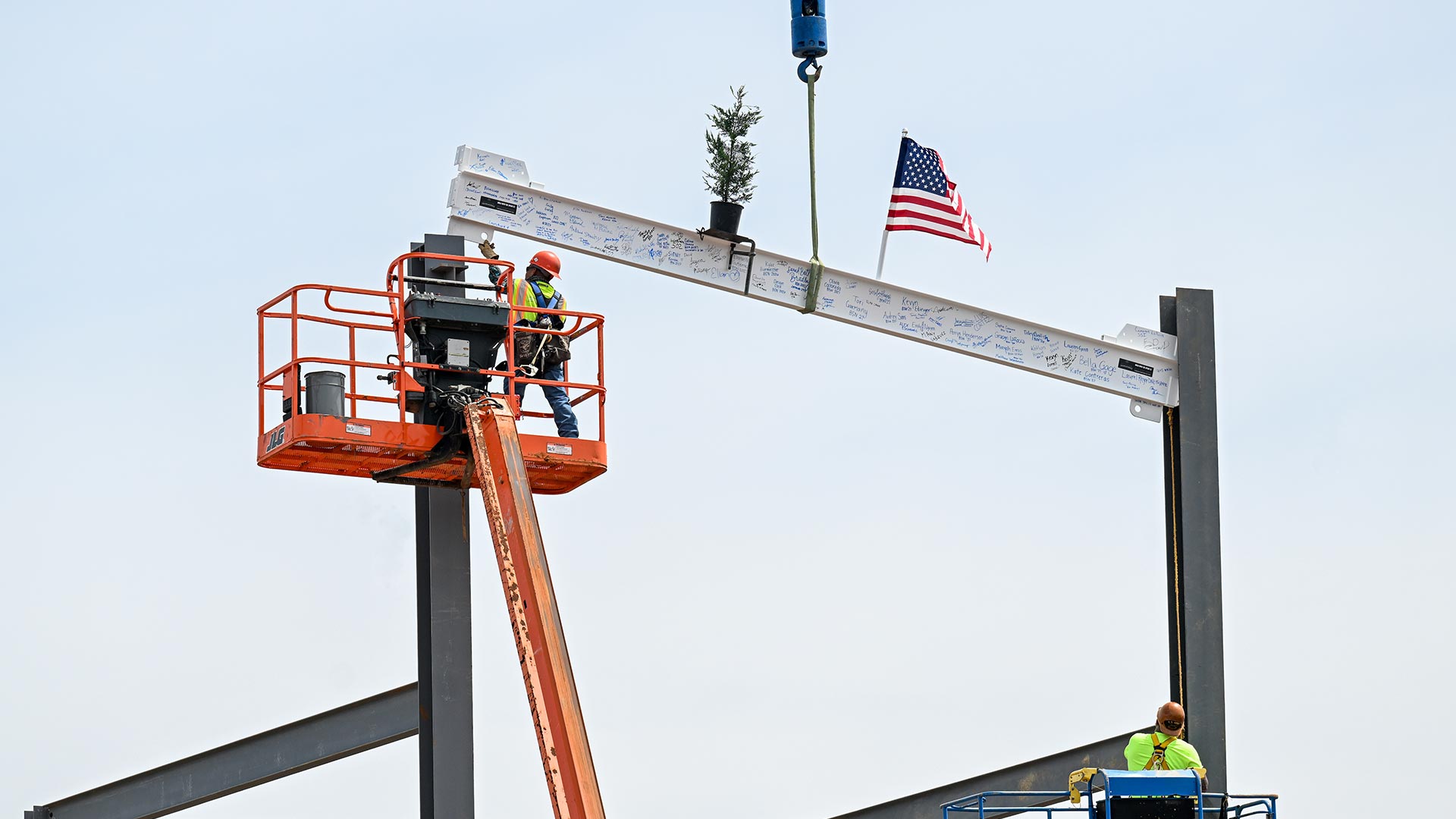 Construction workers placing a top beam on a new building.