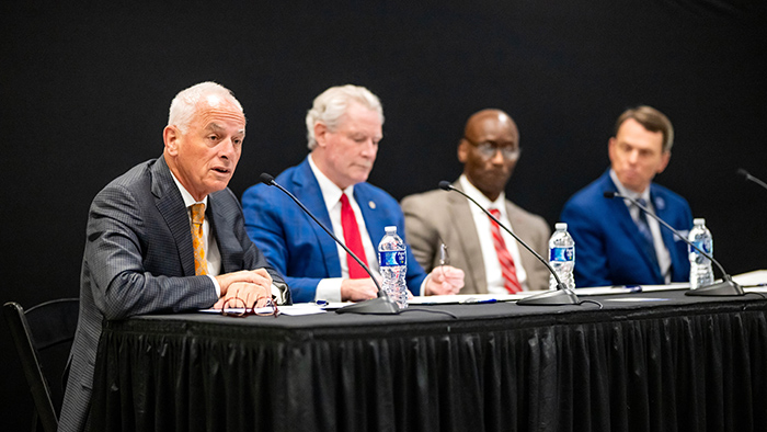 Four men sitting at a table with microphones.