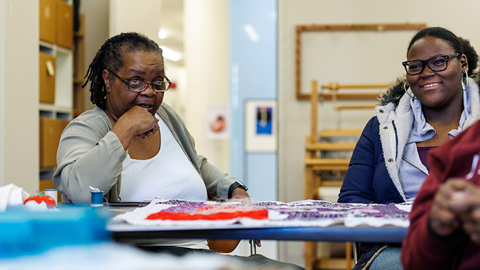Two women talking while working on quilting.