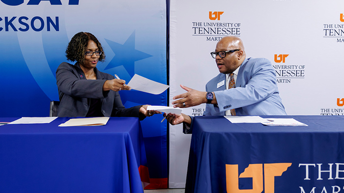 Two people exchanging documents to be signed.