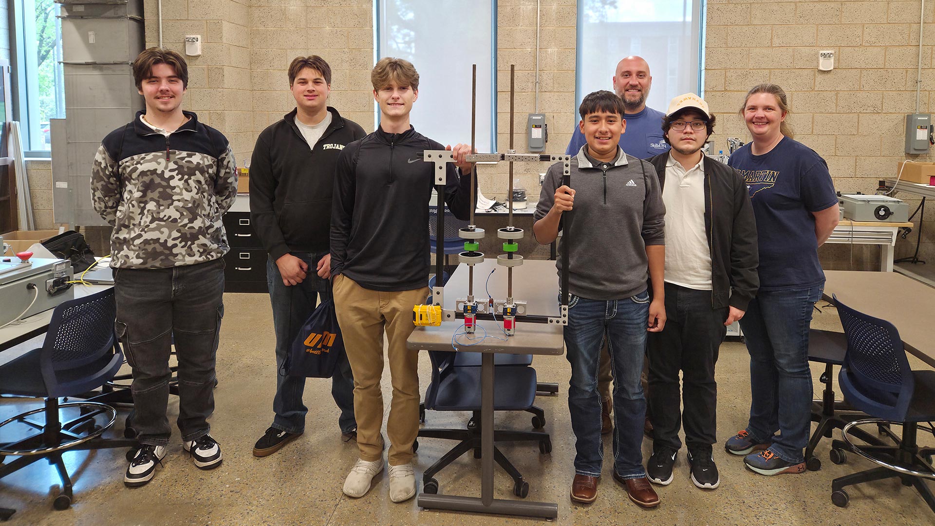 A group of engineering students posing with a piece of equipment.