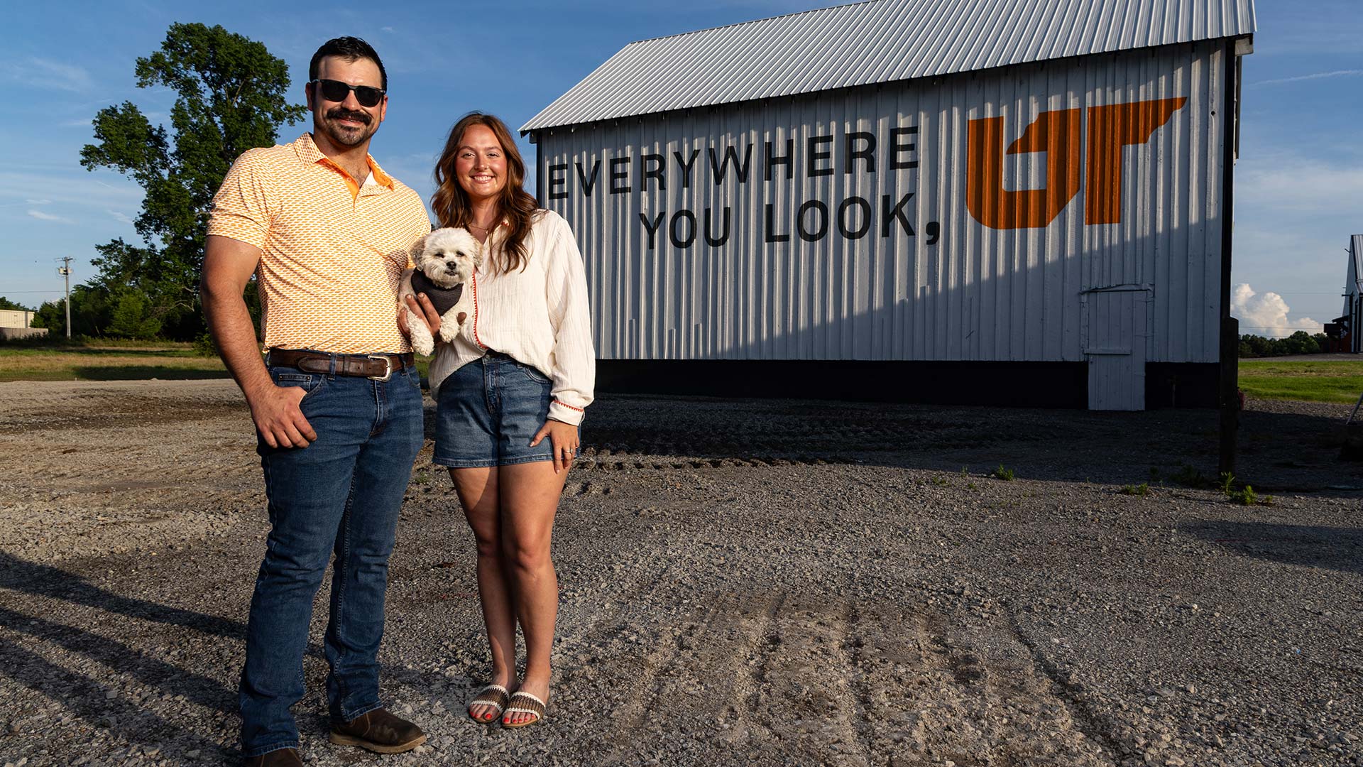 A man and woman standing in front of a painted barn.