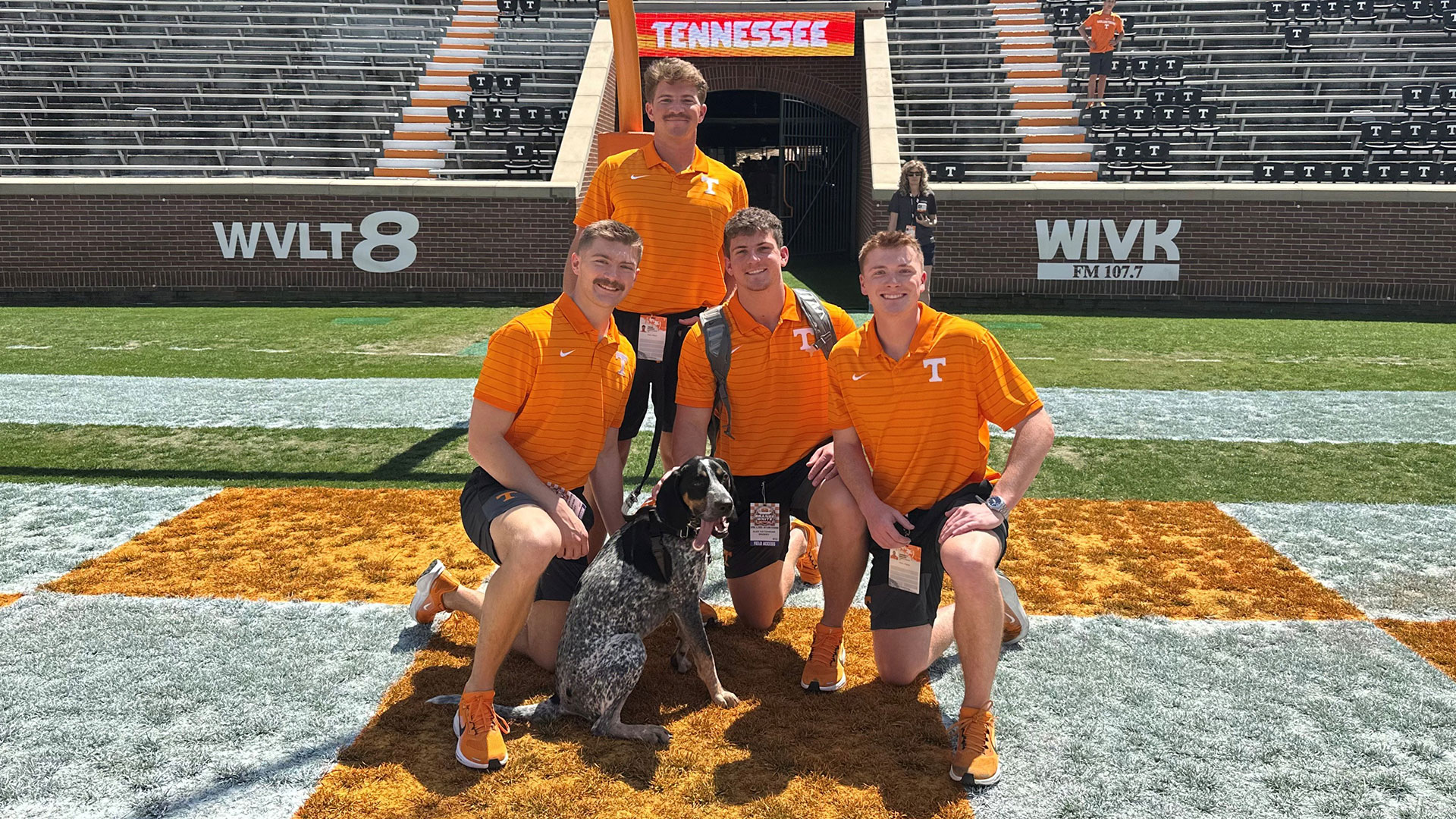 Four men with a bluetick coonhound posing for a photo.