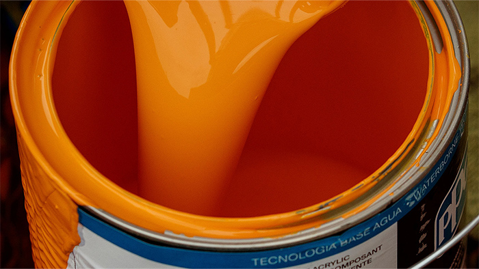 A bucket of orange paint with the lid off.