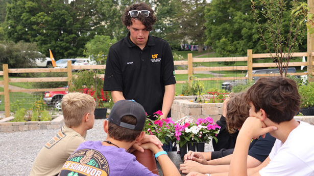 A man talking to a group of middle schoolers about growing flowers.