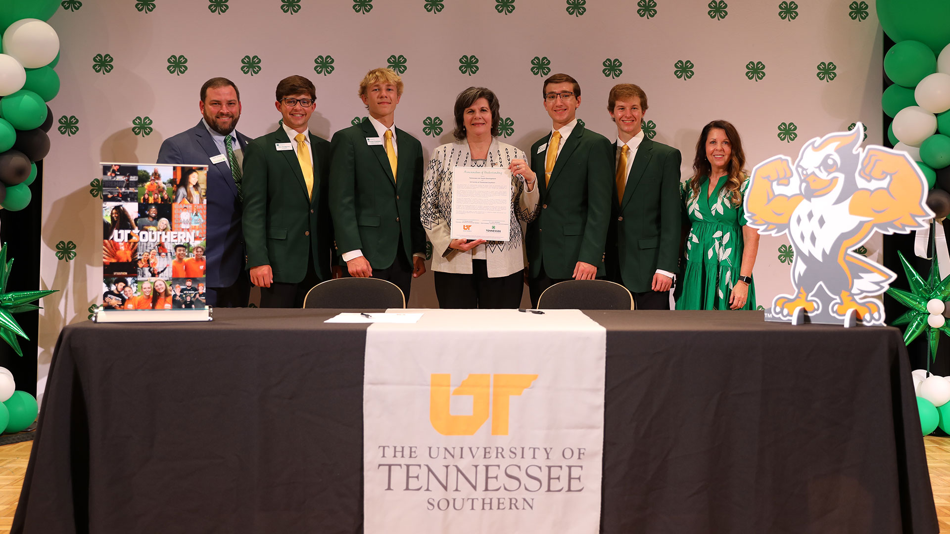 A group of people standing for a photo while holding up a co-signed document.